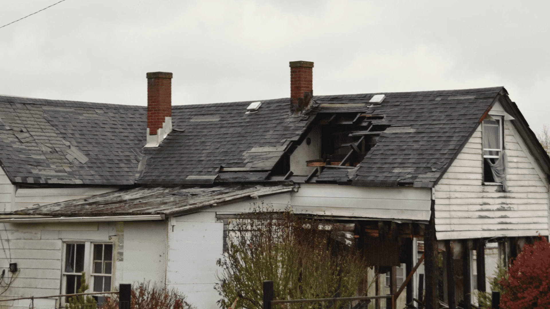 damaged house with a collapsed roof broken shingles and exposed framing showing severe structural deterioration