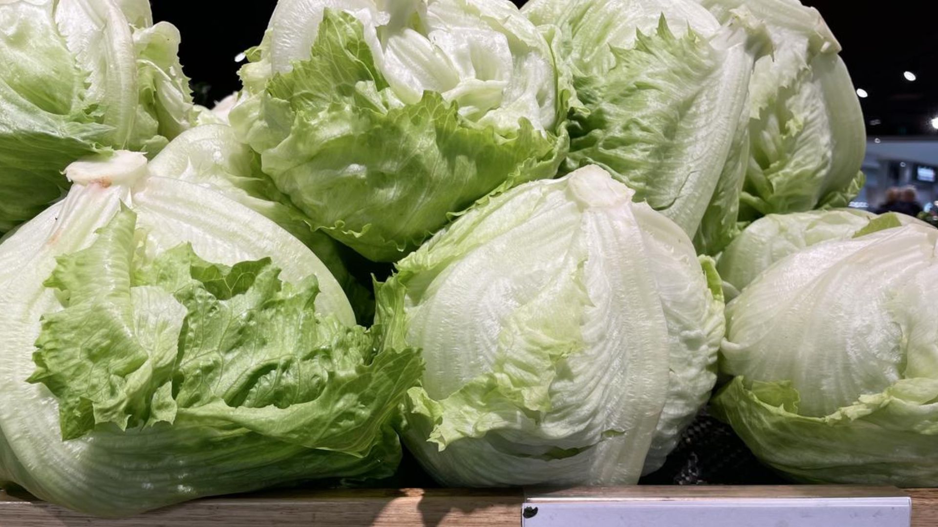 fresh iceberg lettuce heads stacked on a market display showing tightly packed pale green leaves with crisp rounded shape
