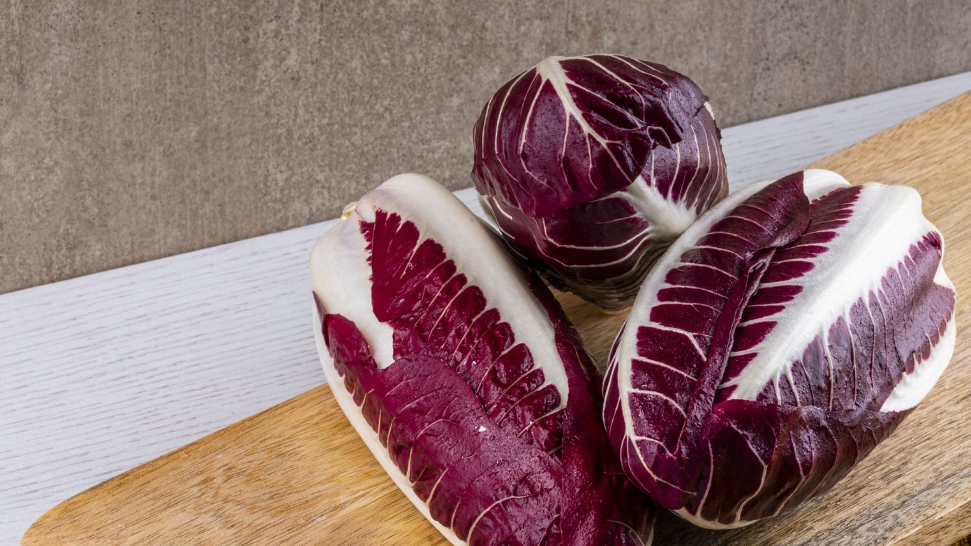fresh radicchio heads with deep red and white crisp leaves resting on a wooden board showing compact layered texture