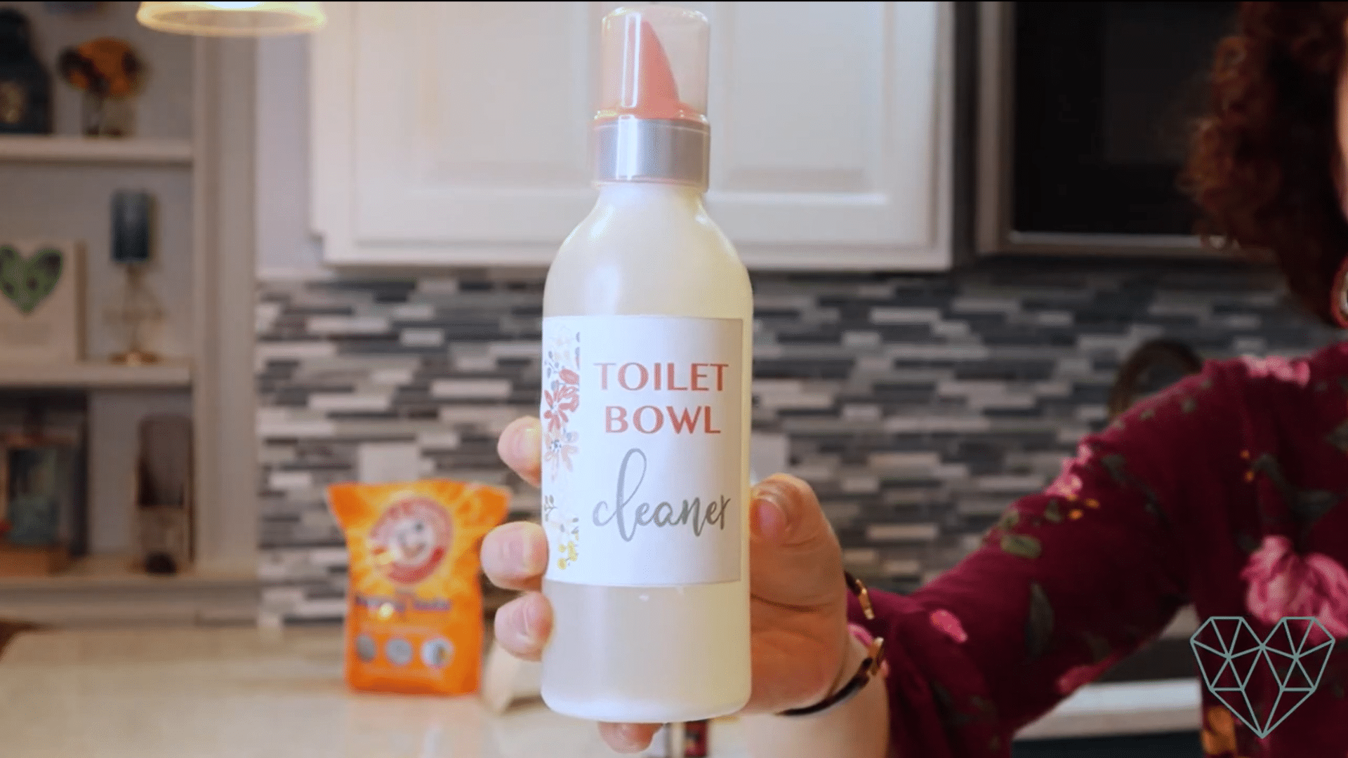 homemade toilet bowl cleaner in a reusable bottle with baking soda and diy cleaning supplies on a kitchen counter
