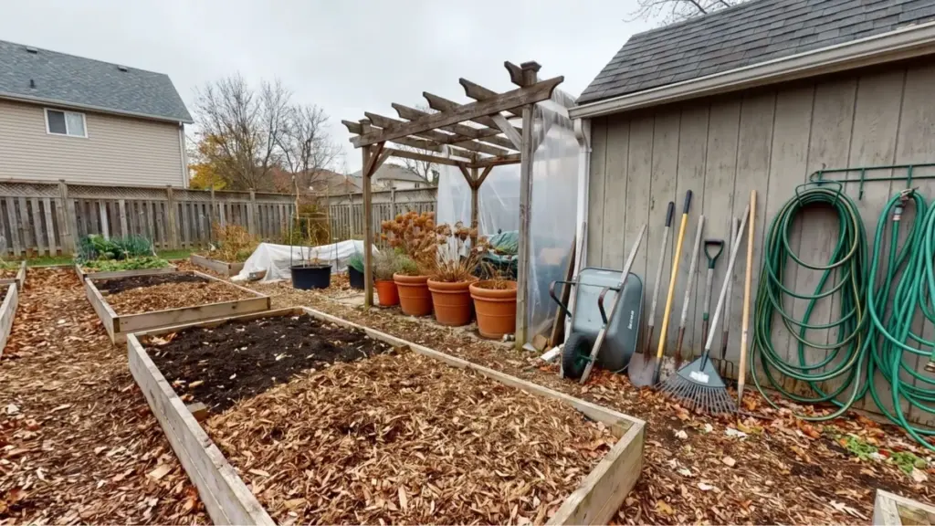 How to Winterize a Garden: 11 Tips Before Winter Fall garden beds with compost, leaf mulch, stored tools, hoses, and container plants prepared for winter