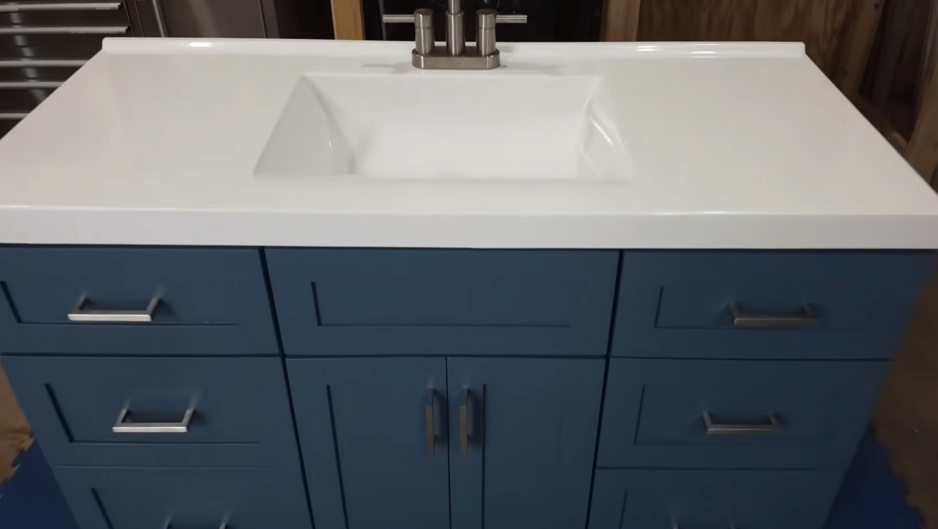 White bathroom vanity cabinet installed with countertop, sink, drawers, and modern hardware.