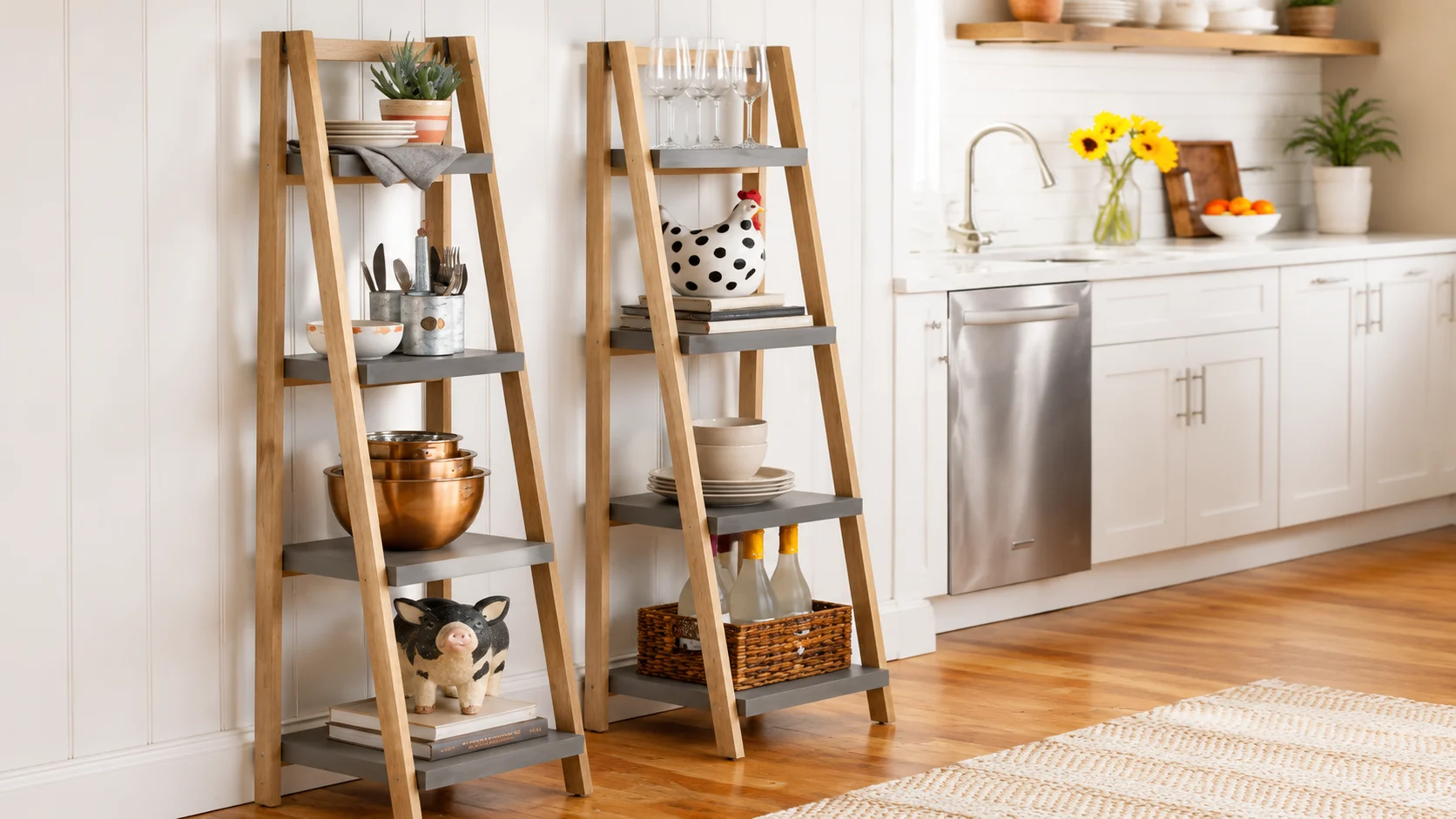 Wooden ladder shelves in a bright kitchen displaying plates, bowls, cookware, decor items, and storage baskets beside white cabinetry.