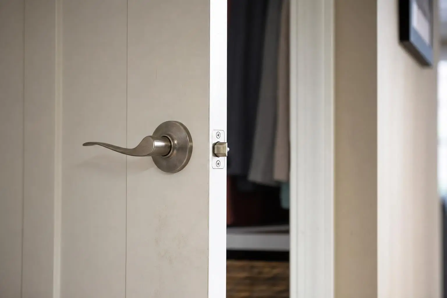 White door slightly open with metal lever handle in a hallway setting