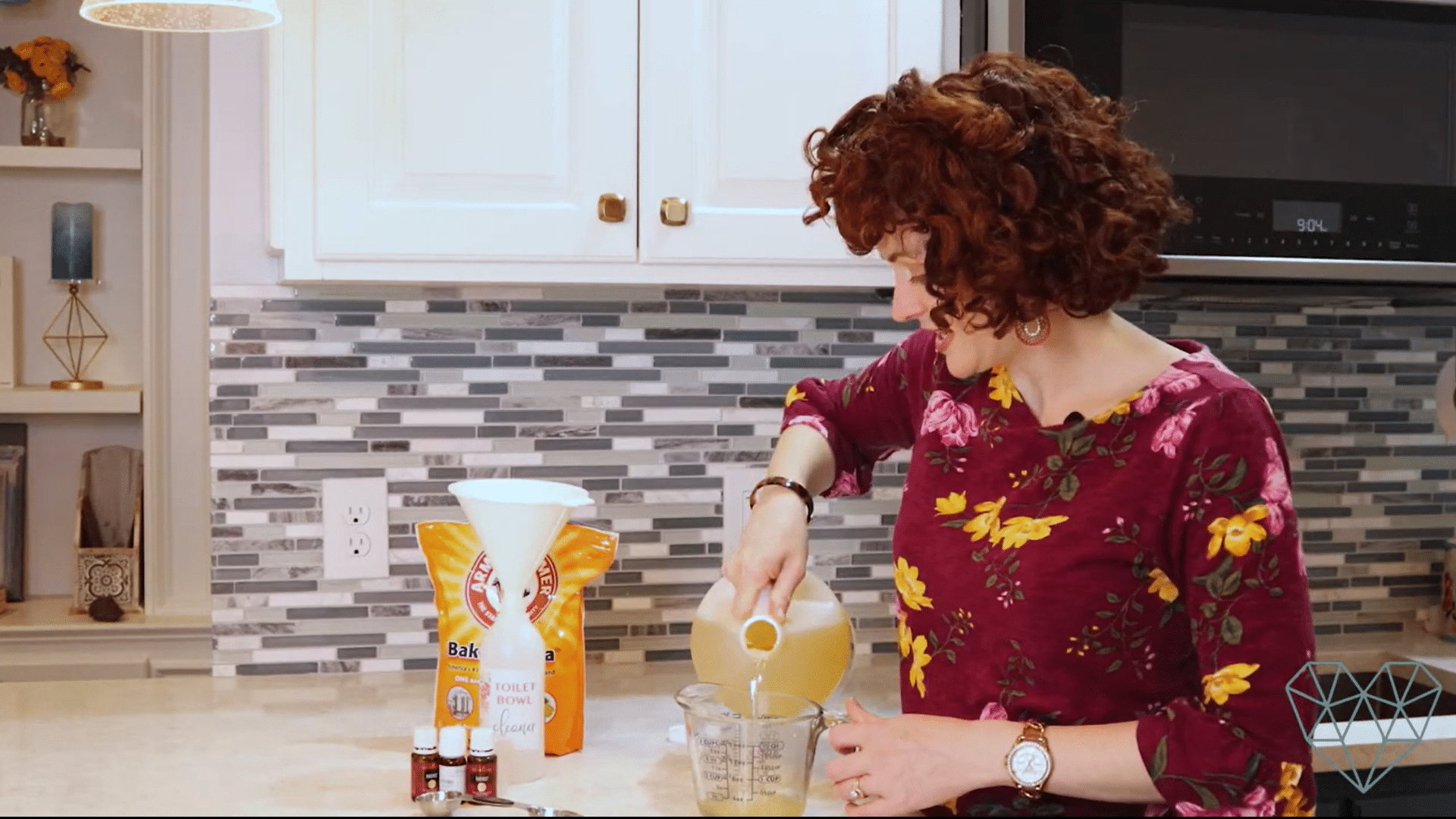 measuring liquid castile soap for a diy toilet bowl cleaner recipe with baking soda essential oils reusable bottle and funnel on a kitchen counter