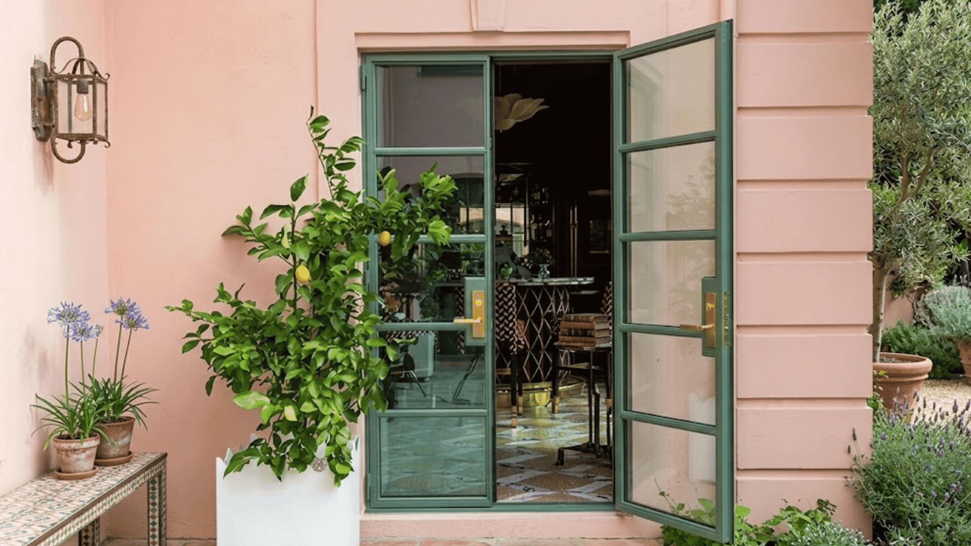 open green framed french doors leading into a stylish home beside potted plants and a peaceful garden courtyard