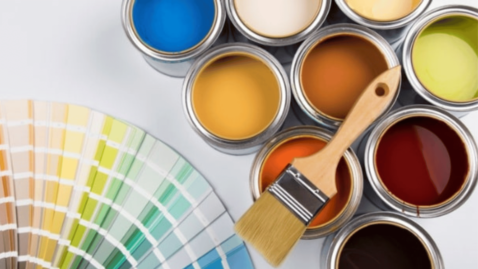paint cans in various colors with a paintbrush resting across them beside a fanned out paint color swatch palette
