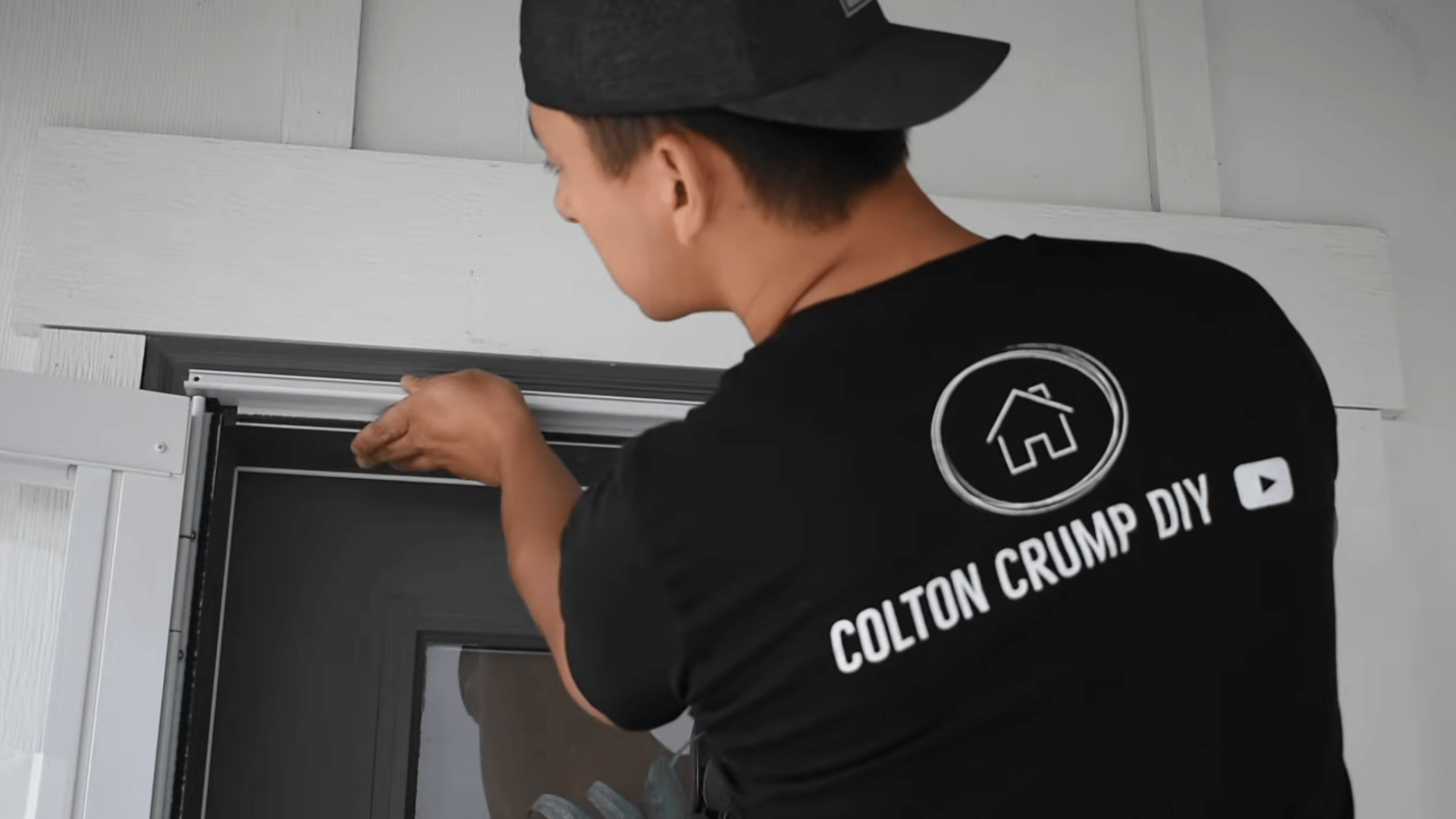person adjusting the top sweep on a white storm door to align it properly before completing the installation process