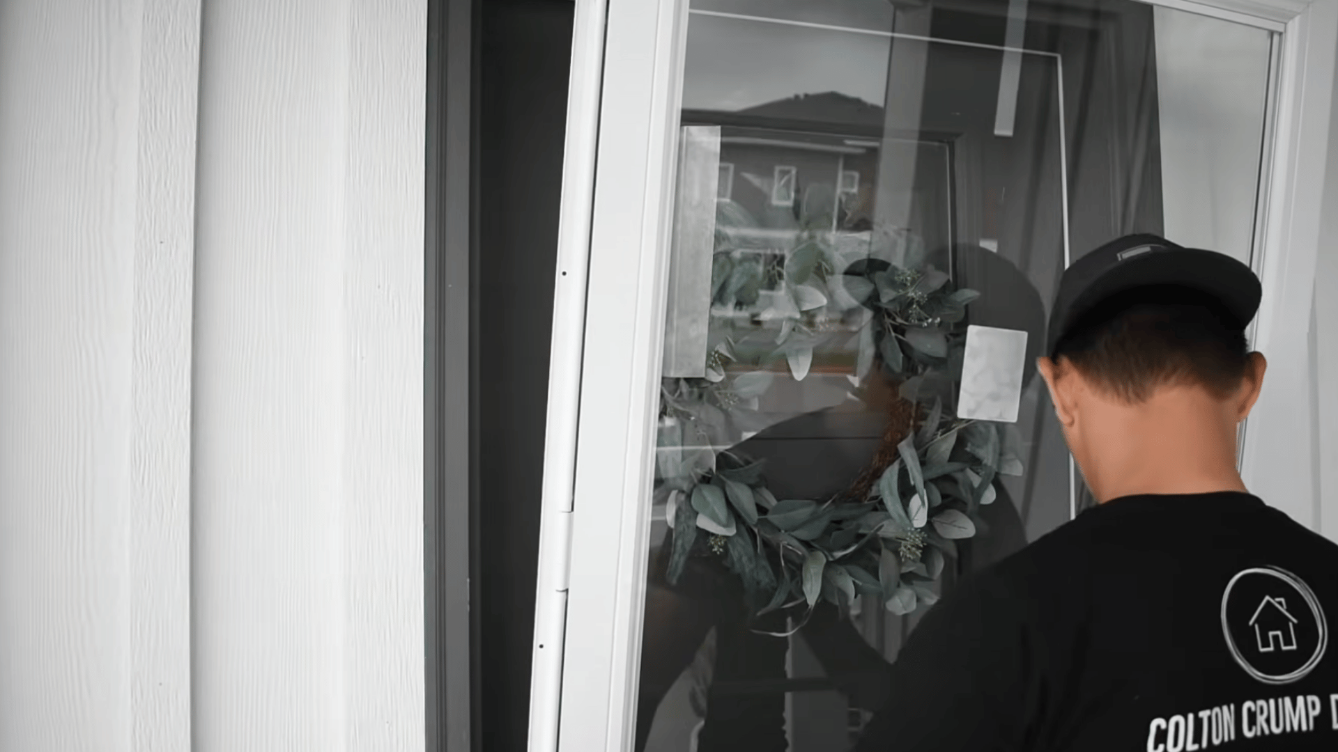 person positioning a white storm door in the doorway while aligning the frame before securing it to the exterior entrance