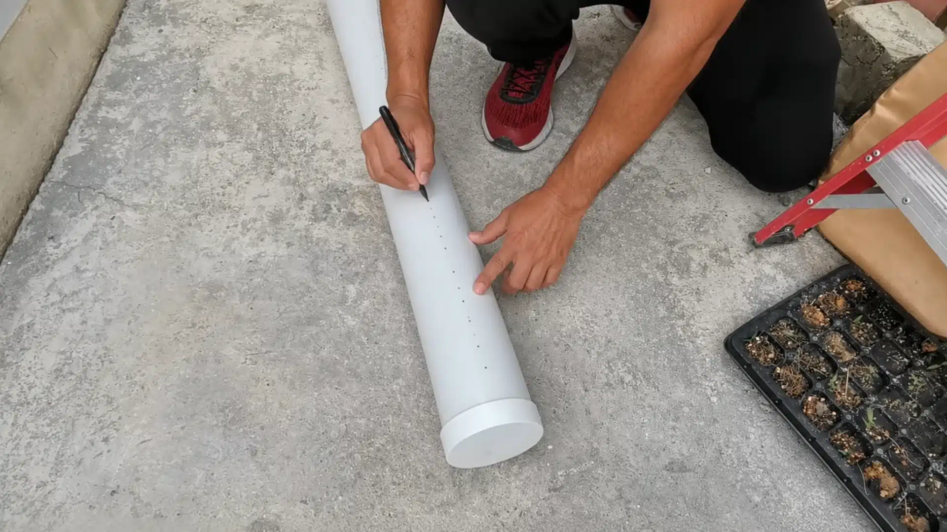 measuring and marking pvc pipe for a diy hydroponic system setup before drilling planting holes