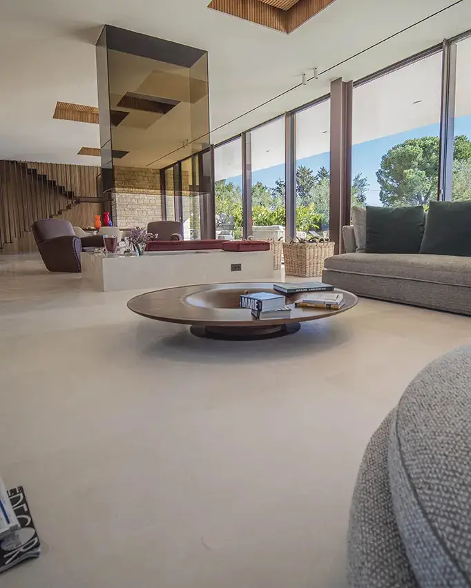 Renovating With Natural Stone: The Timeless Appeal of Trani Biancone Between Elegance, Functionality, and Sustainability Spacious modern living room with large windows, gray furniture, and wooden coffee table