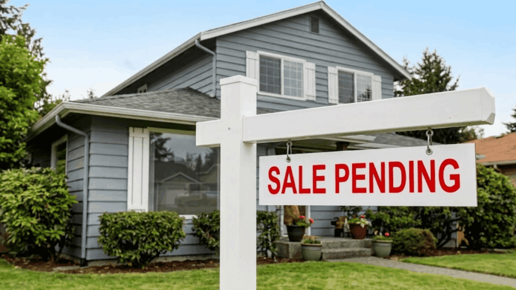 What Does Pending & Contingent Mean in Real Estate? sale pending sign stands in front of a gray two story house with trimmed shrubs and a green front lawn
