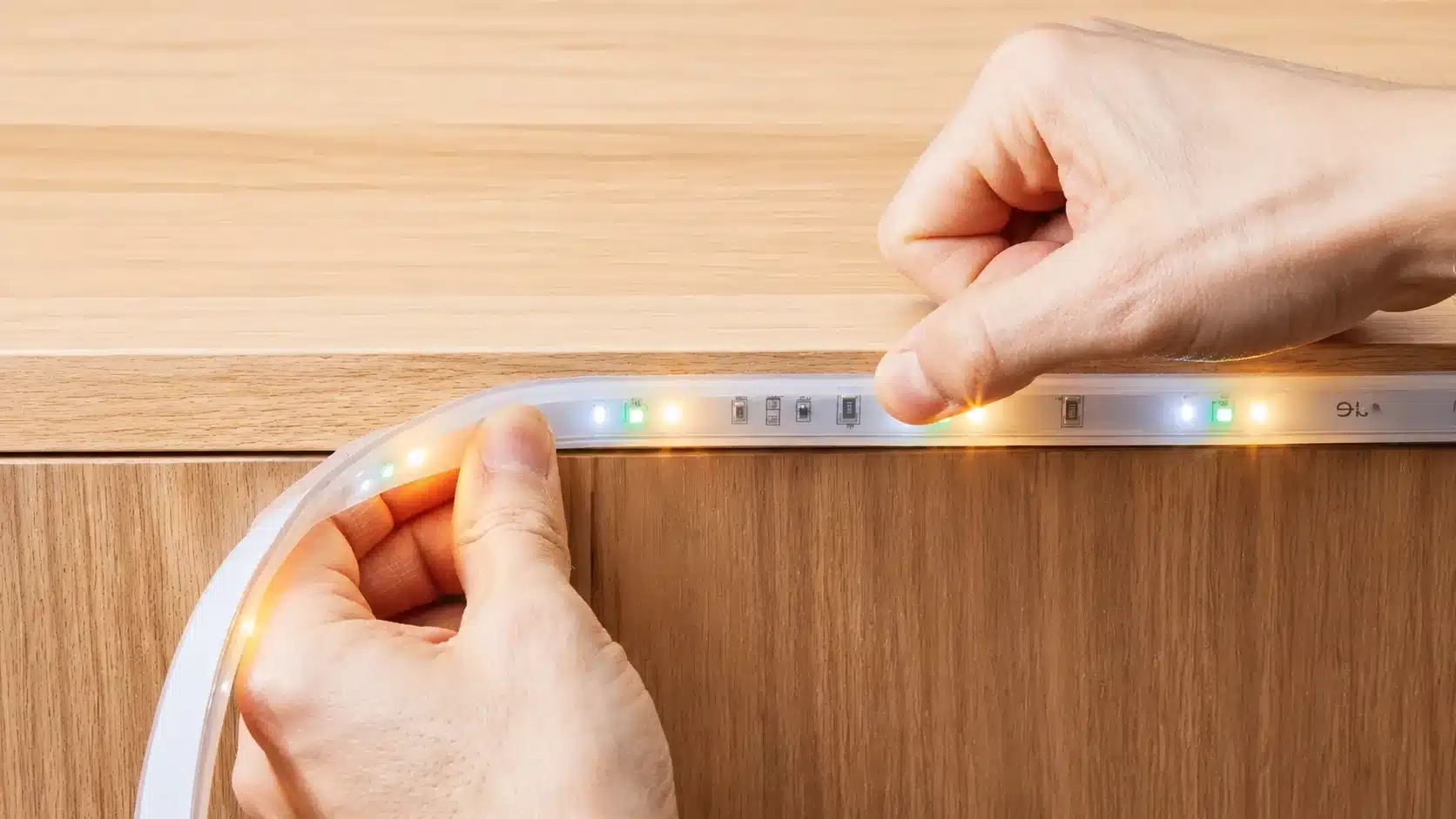 Stick-on LED light strip installed under a shelf, providing soft illumination for a home storage area.