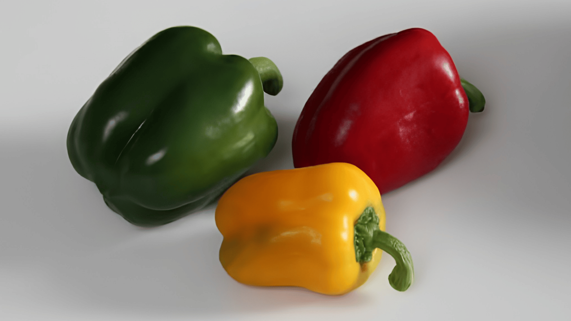 three green red and yellow bell peppers arranged together on a white surface showing fresh colorful vegetables ready for cooking