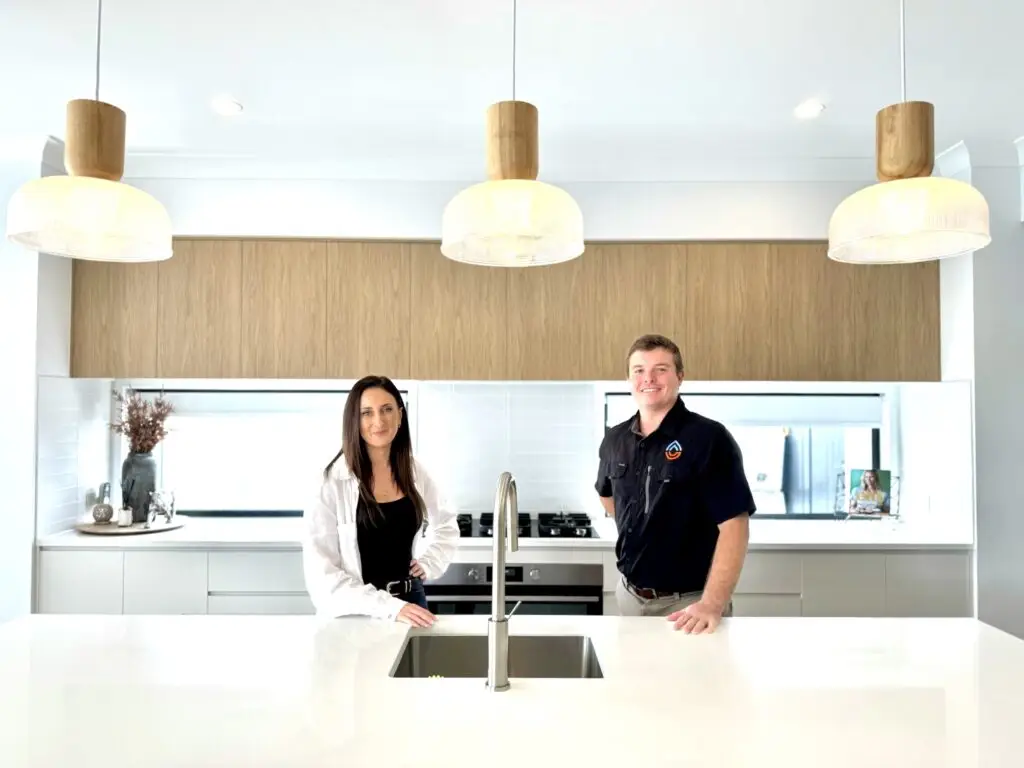 What to Do Before Your Emergency Plumber in Brisbane Arrives People standing at modern kitchen island with pendant lights and wood cabinetry