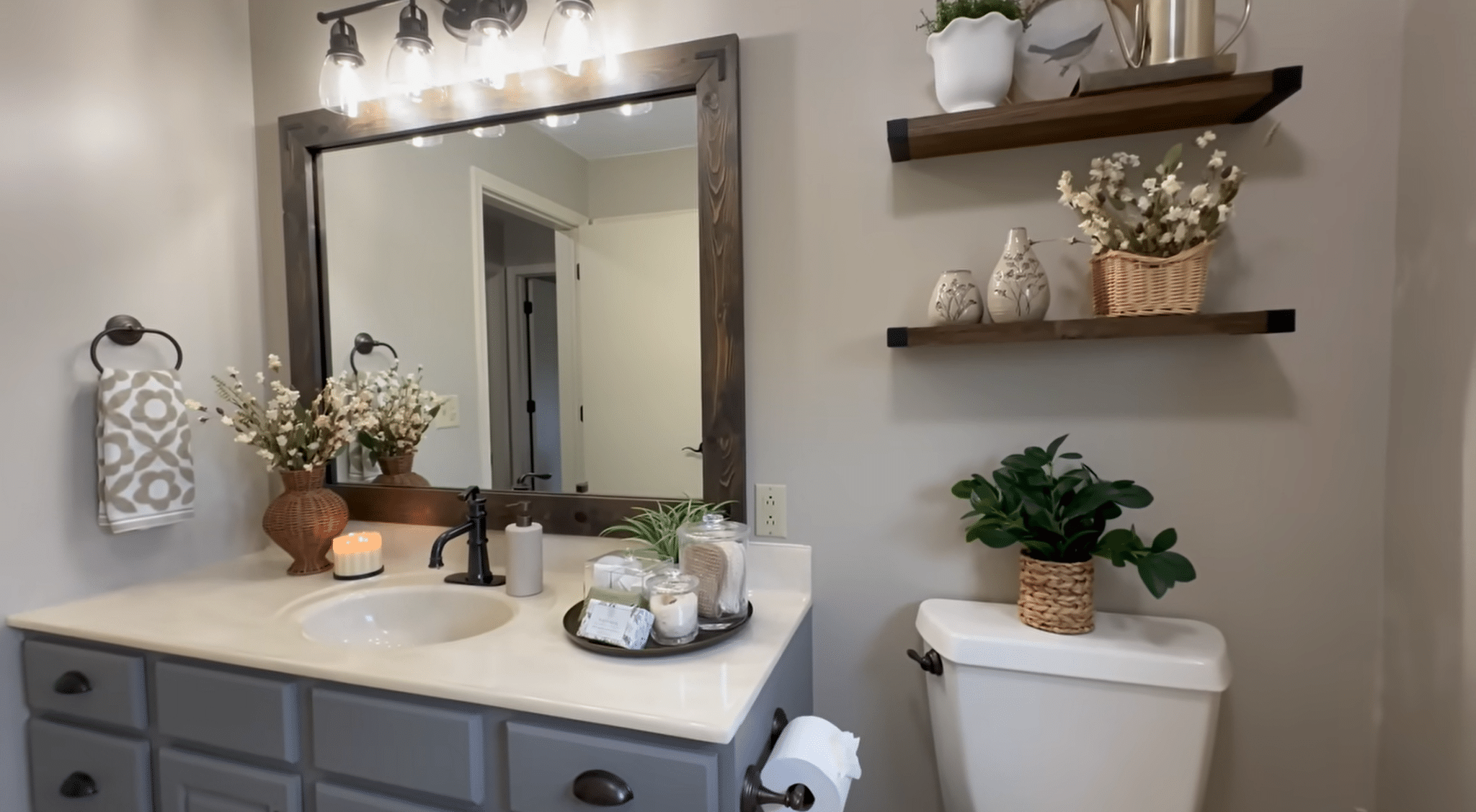 Bathroom vanity styled with plants, candles, shelves, and decorative accessories for a finished look.