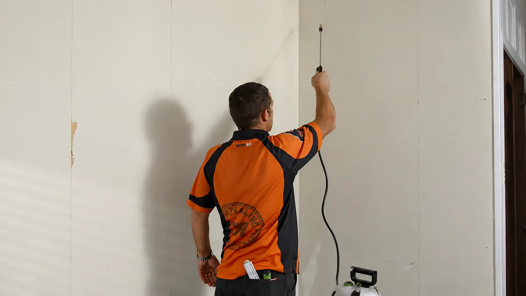 Person using a wallpaper removal tool on a wall surface during a home renovation project.