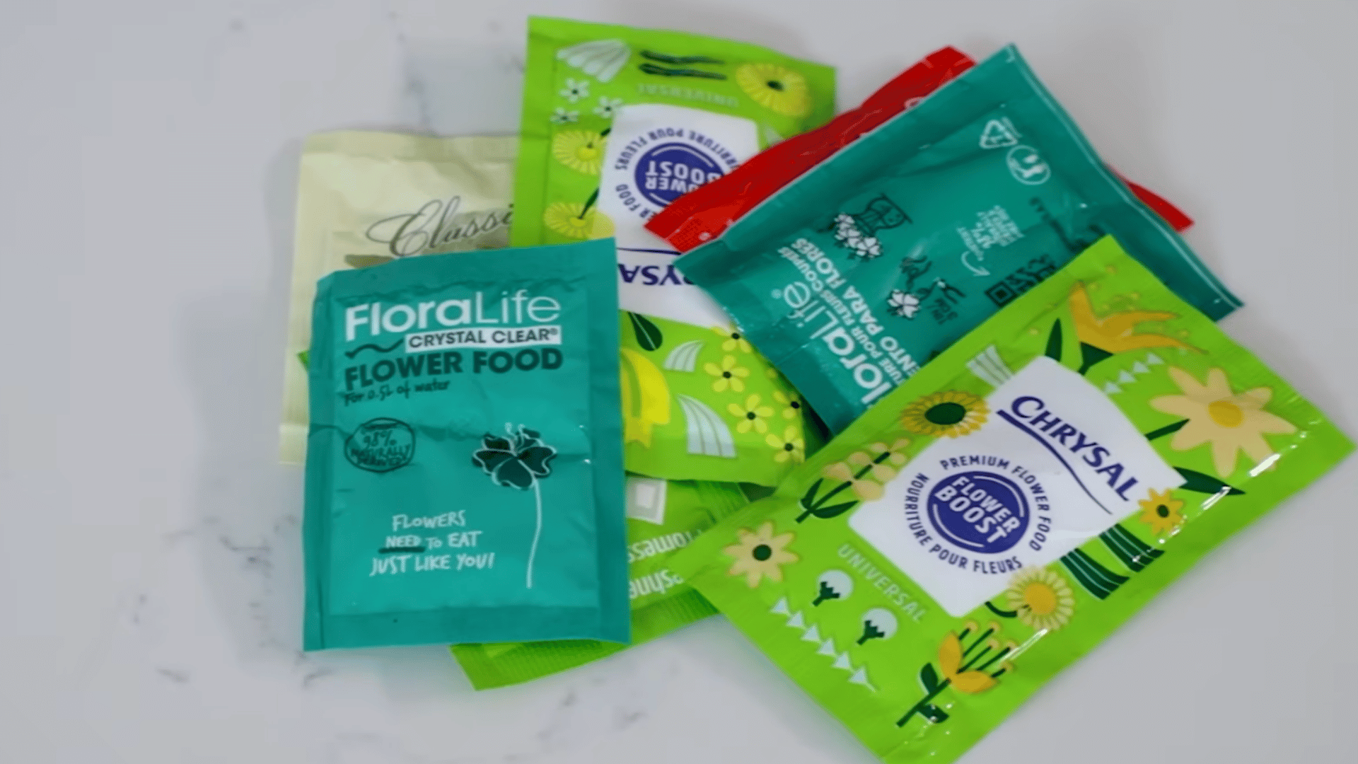 assorted flower food packets are spread across a countertop showing different preservatives used to keep cut flowers fresh longer