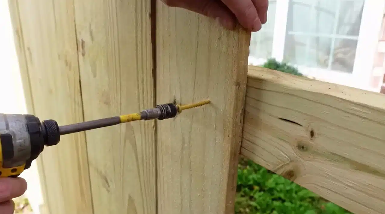 Attaching wooden fence pickets with screws to complete a backyard fence panel