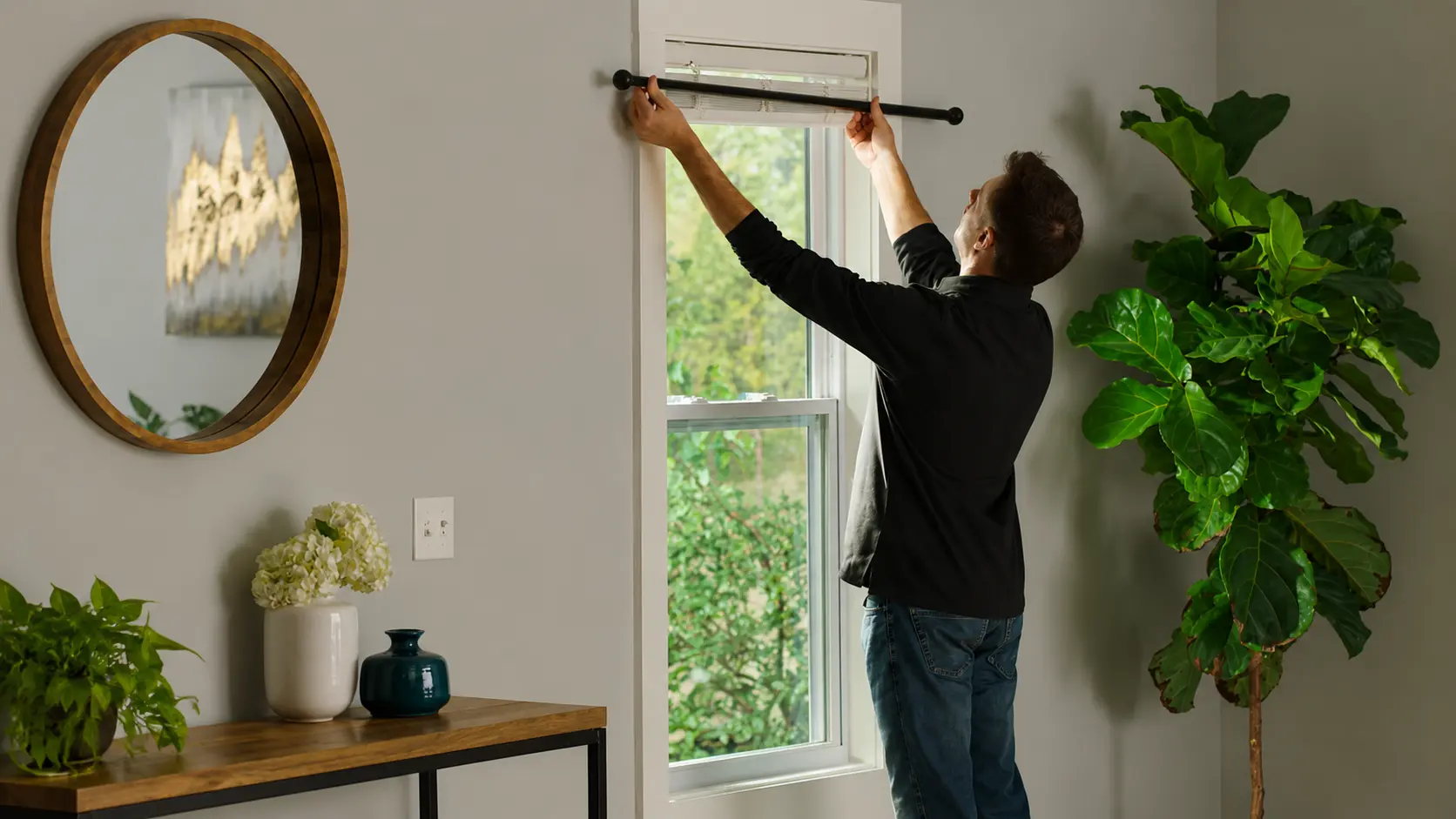 Man measuring curtain rod above a window