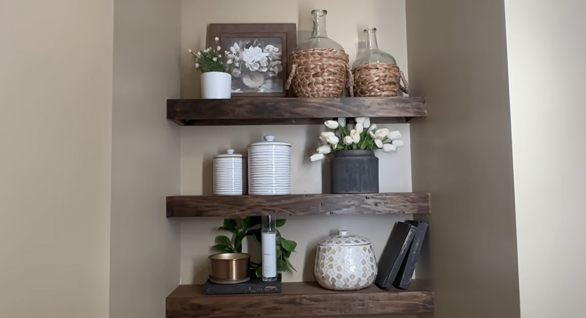 Bathroom floating shelves styled with plants, baskets, vases, and decorative items for a layered look.