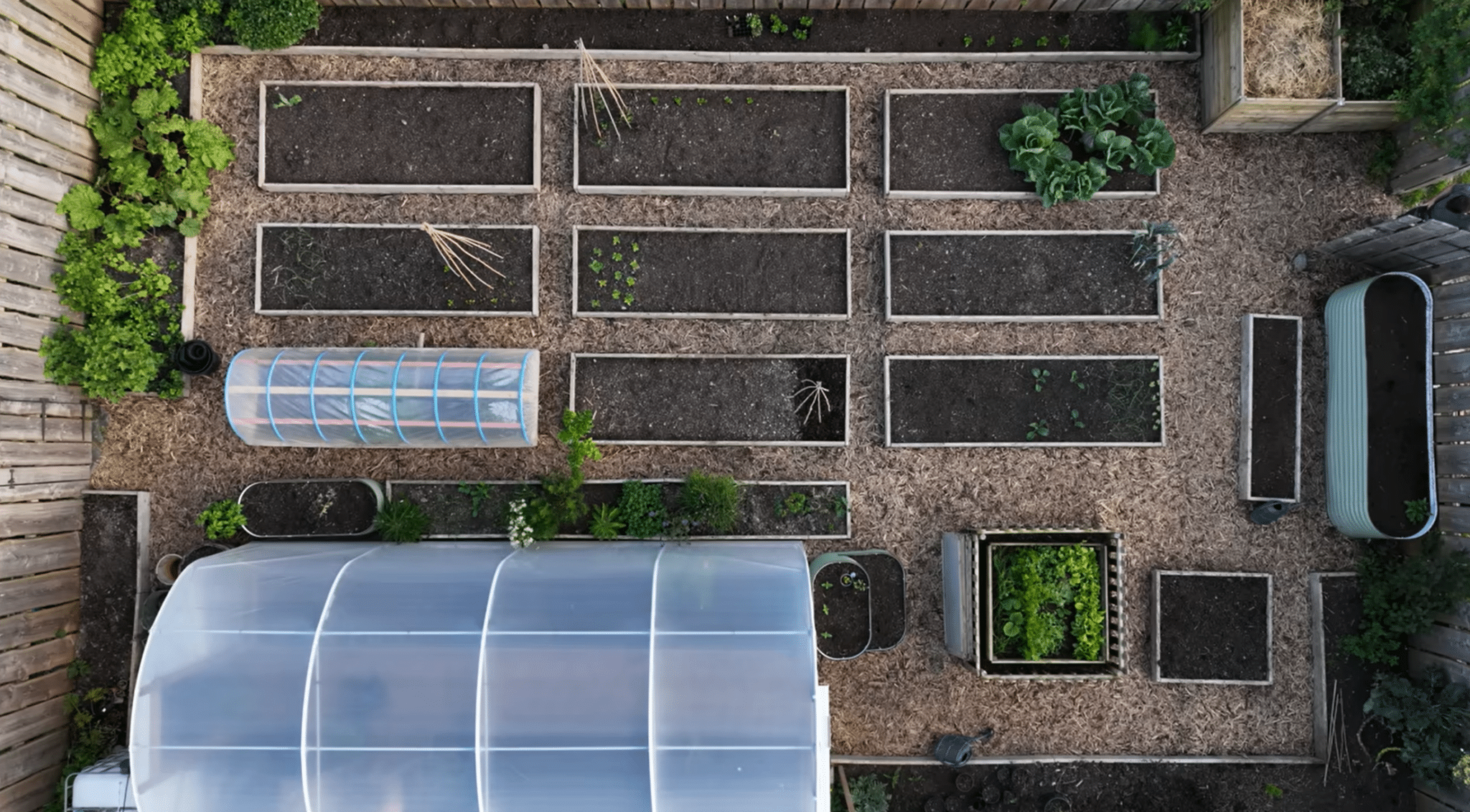 Aerial view of a potager garden layout with raised beds, pathways, greenhouse, and organized planting areas.