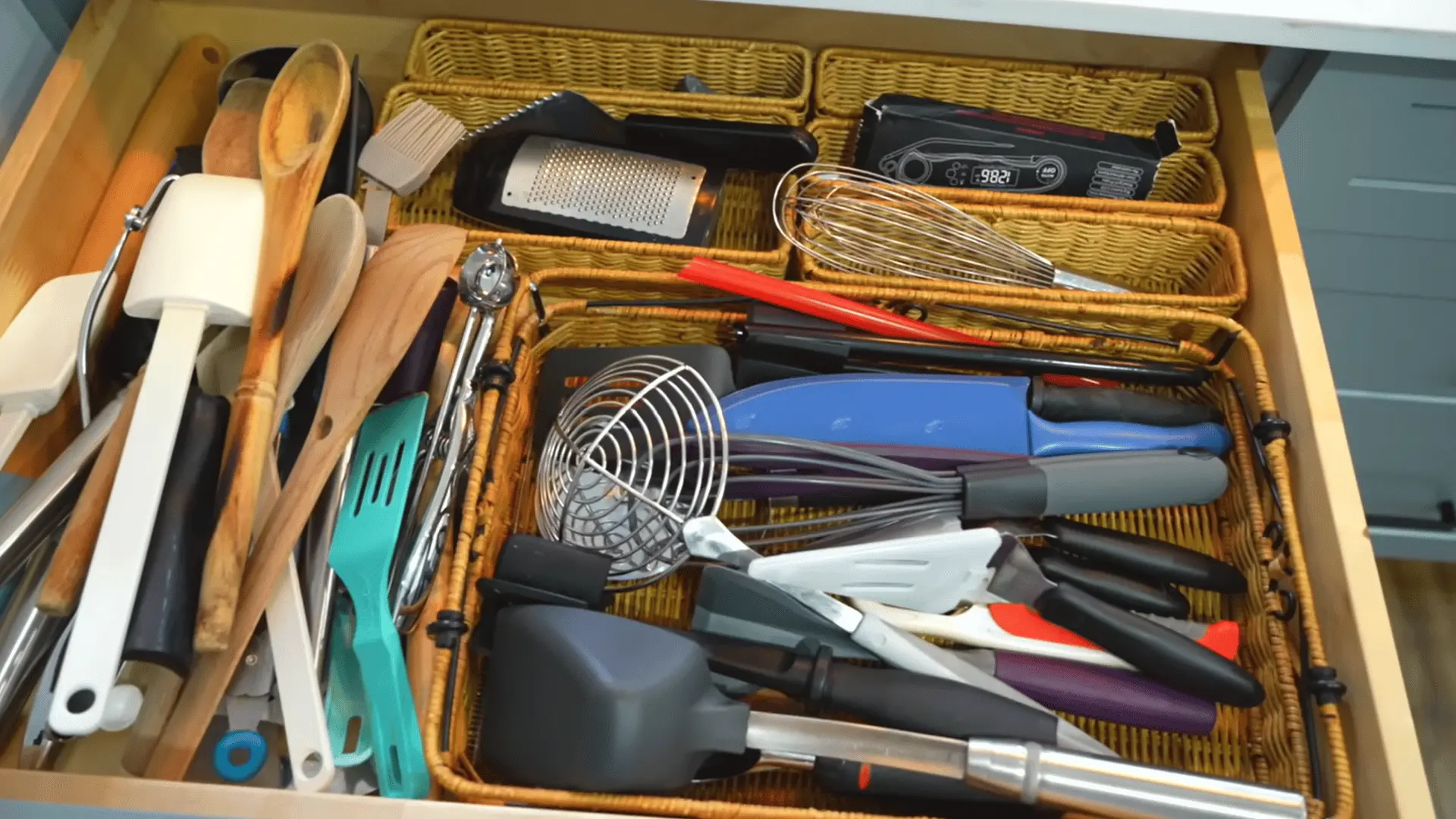 Kitchen utensil drawer being sorted to remove duplicate spatulas, whisks, spoons, and other cooking tools.
