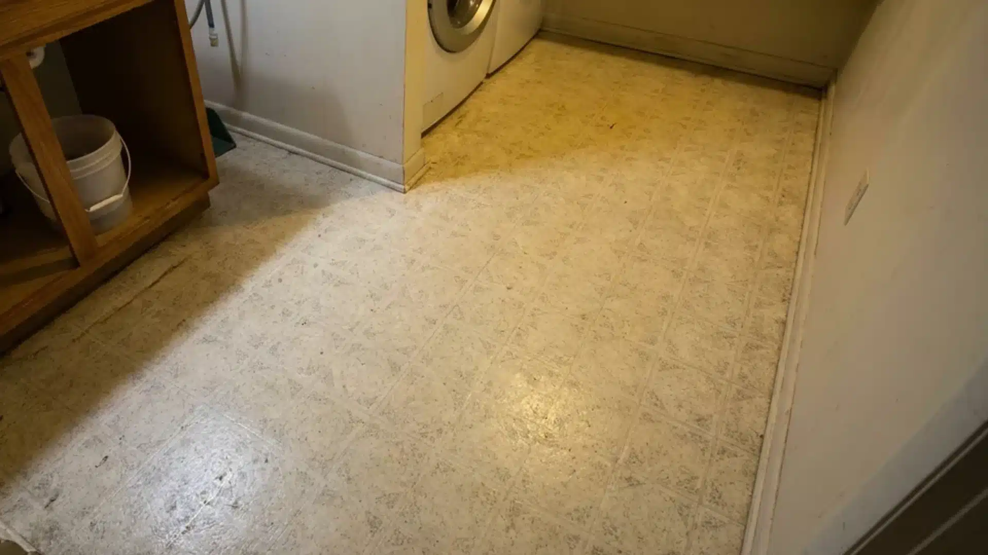 linoleum sheet flooring installed in a small utility room near a sink cabinet base