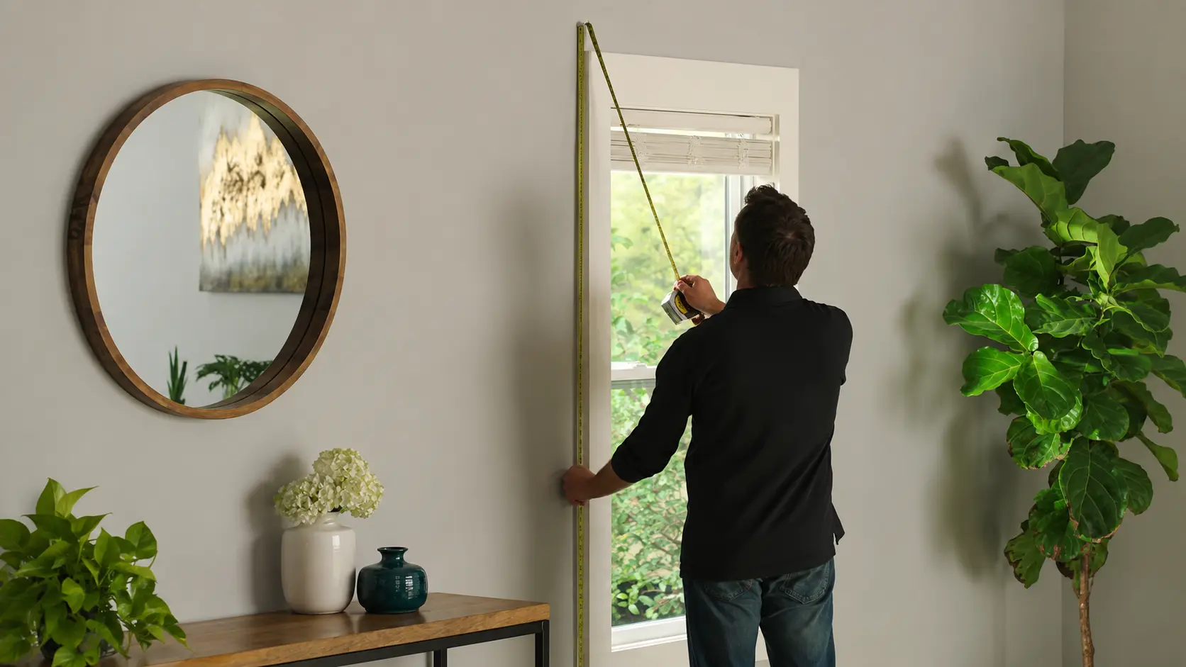 Man measuring a window frame with a tape measure