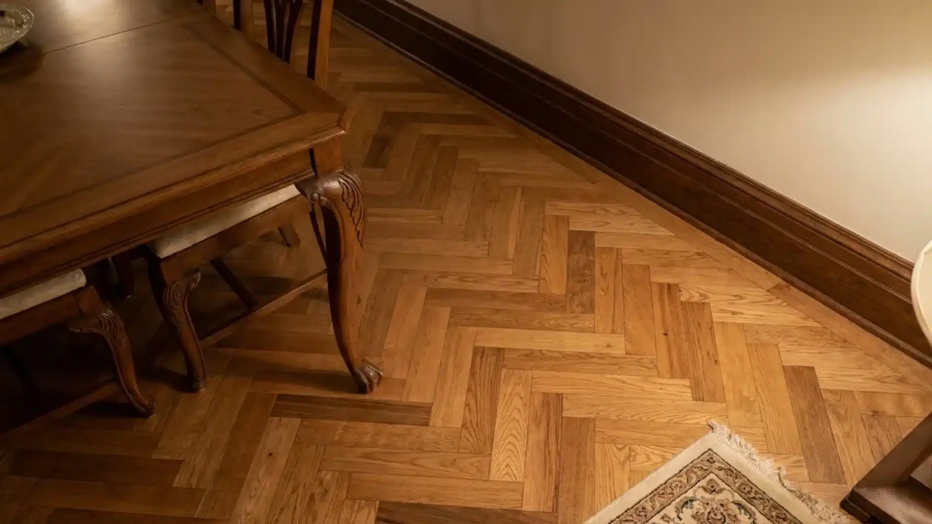 geometric herringbone parquet wood flooring installed in a formal dining room corner