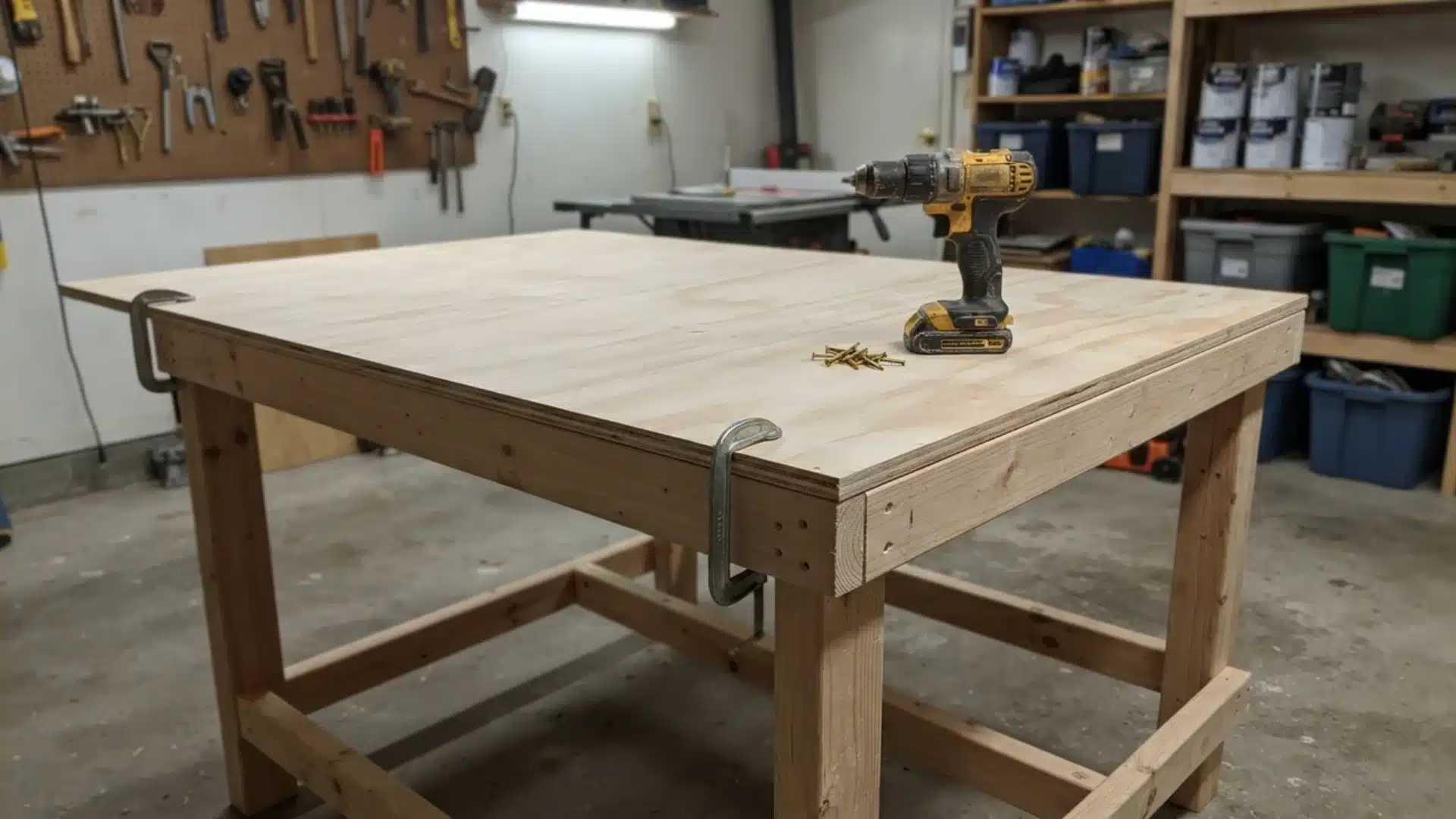 Plywood tabletop clamped to wooden workbench frame with a drill and screws sitting on top.
