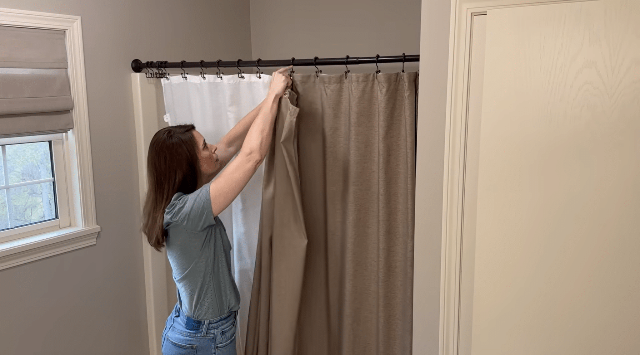 Person installing a new shower curtain to refresh a bathroom space with a simple decor update.