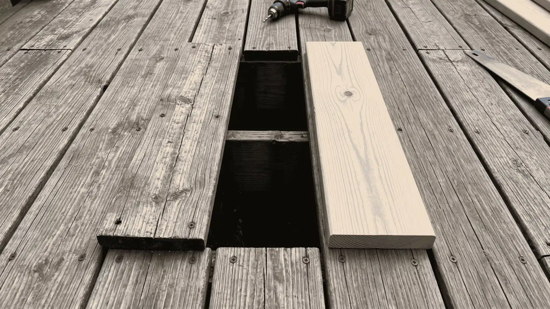 Replacement deck board beside an open space among intact wooden boards