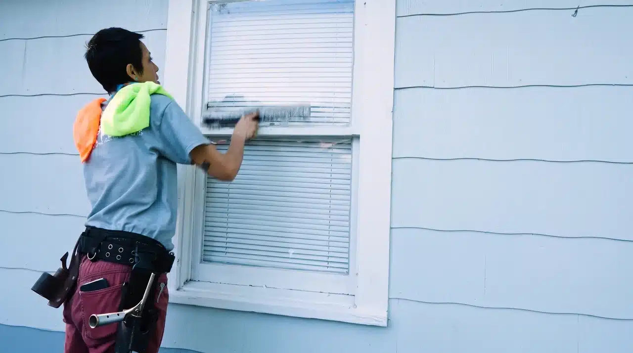 Window cleaner washing the upper glass pane with a soft window scrubber.