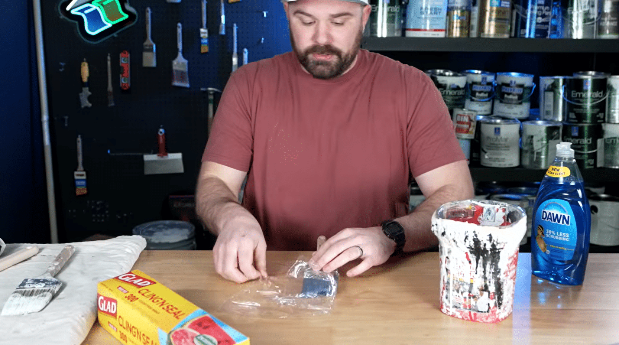 Person wrapping a paint brush in cling wrap to keep the bristles wet before cleaning.