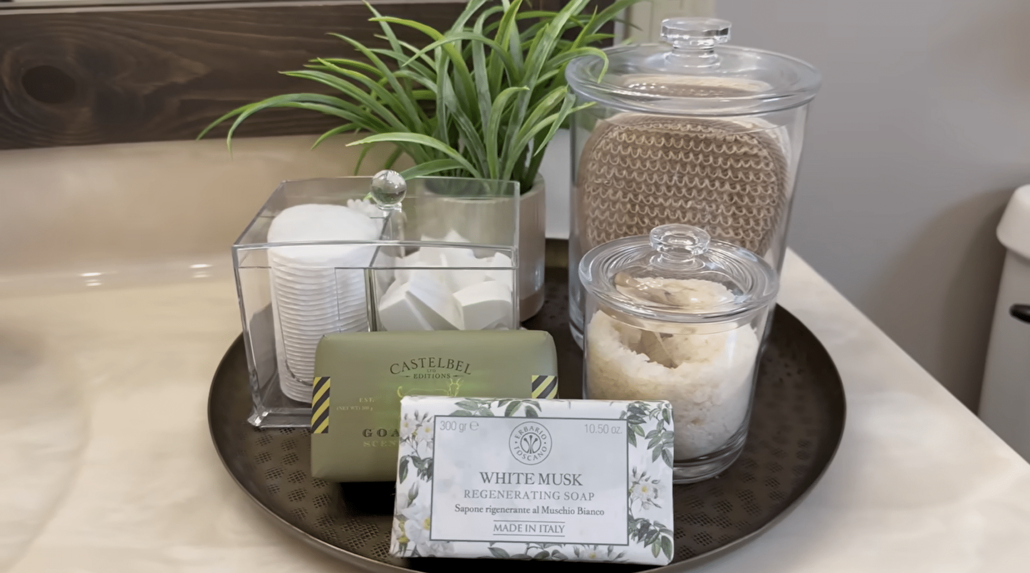 Bathroom countertop tray styled with clear containers, soap, and greenery for organized decor.