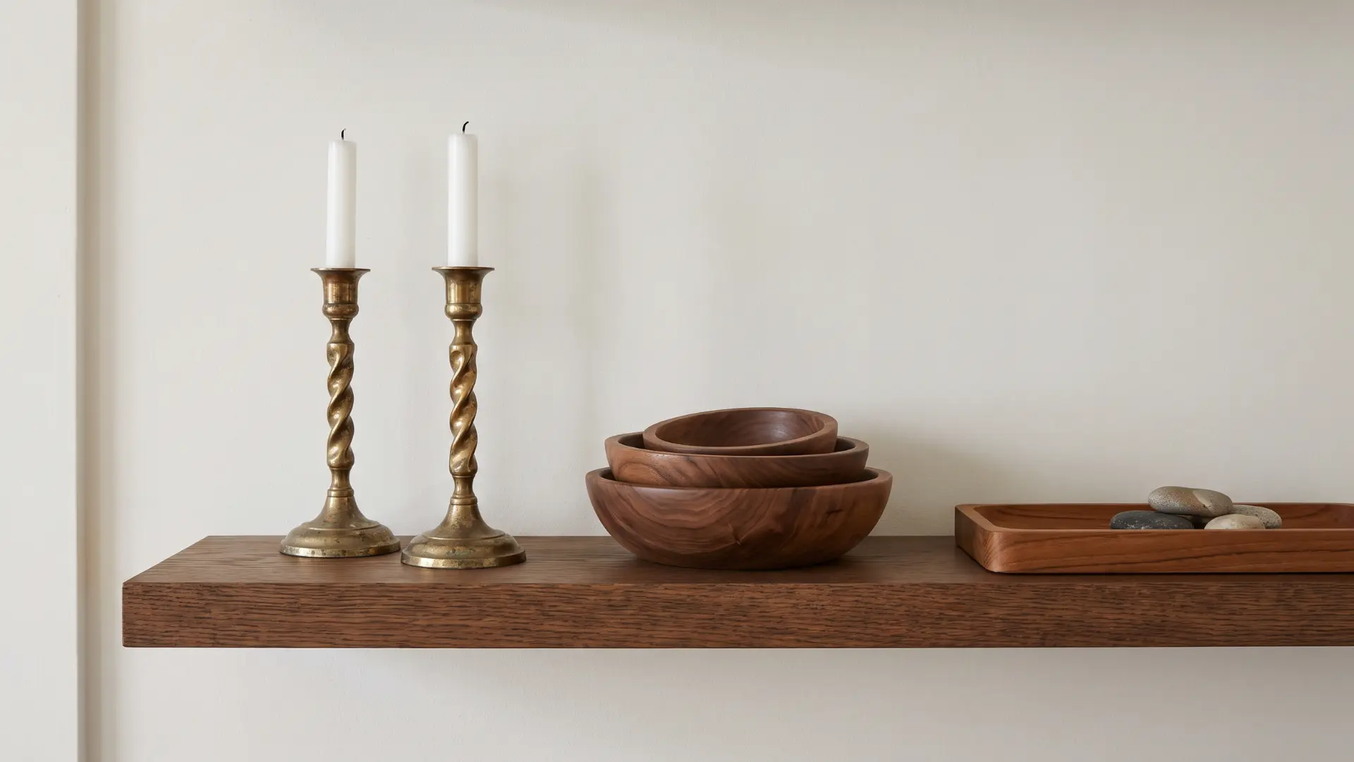 Brass candlesticks paired with wood bowls on a shelf