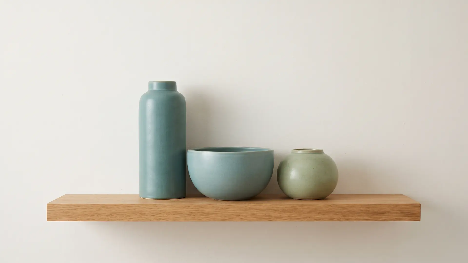 Three matching-tone vases of different shapes grouped on a shelf