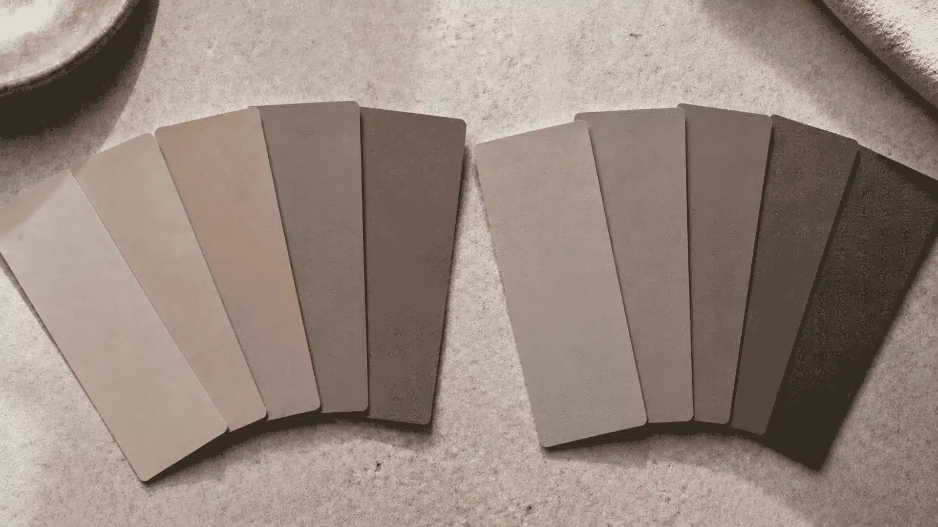 Warm and cool taupe paint swatches arranged side by side on a stone surface