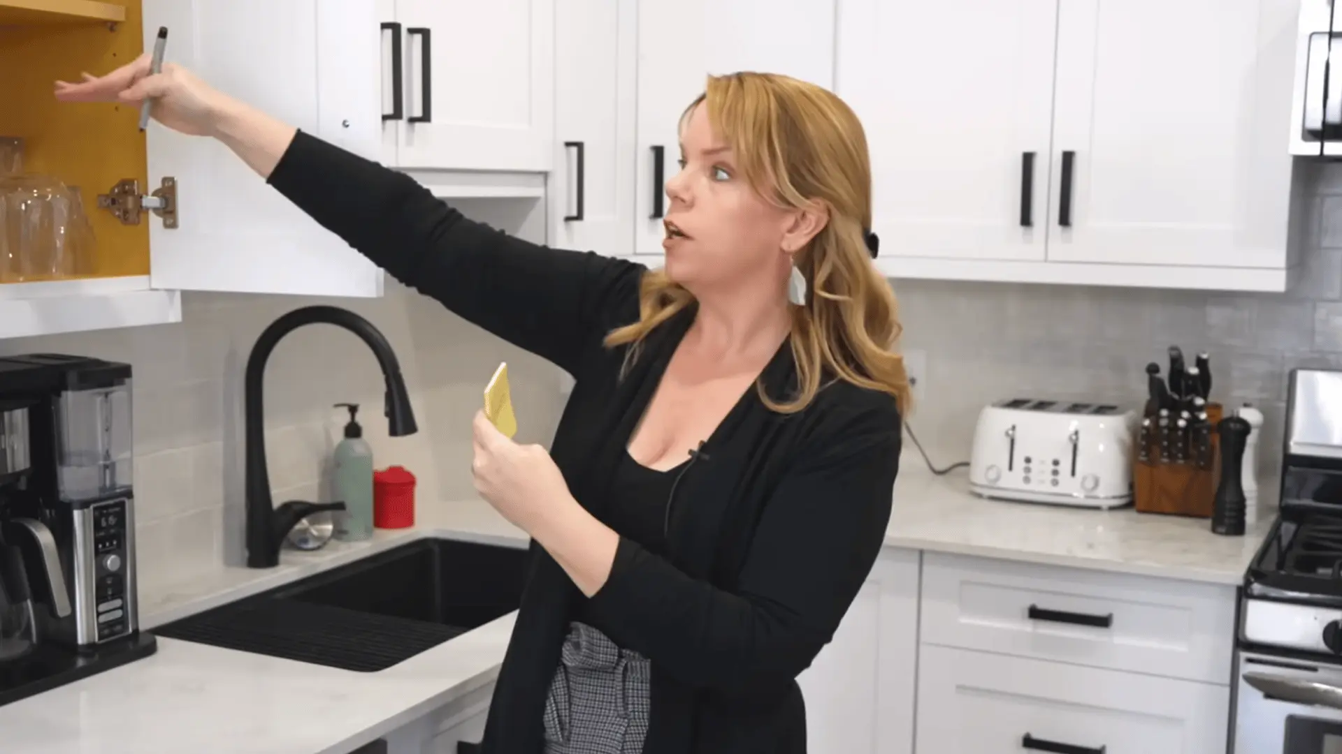 Woman uses sticky notes to assign everyday glasses to an accessible upper kitchen cabinet.
