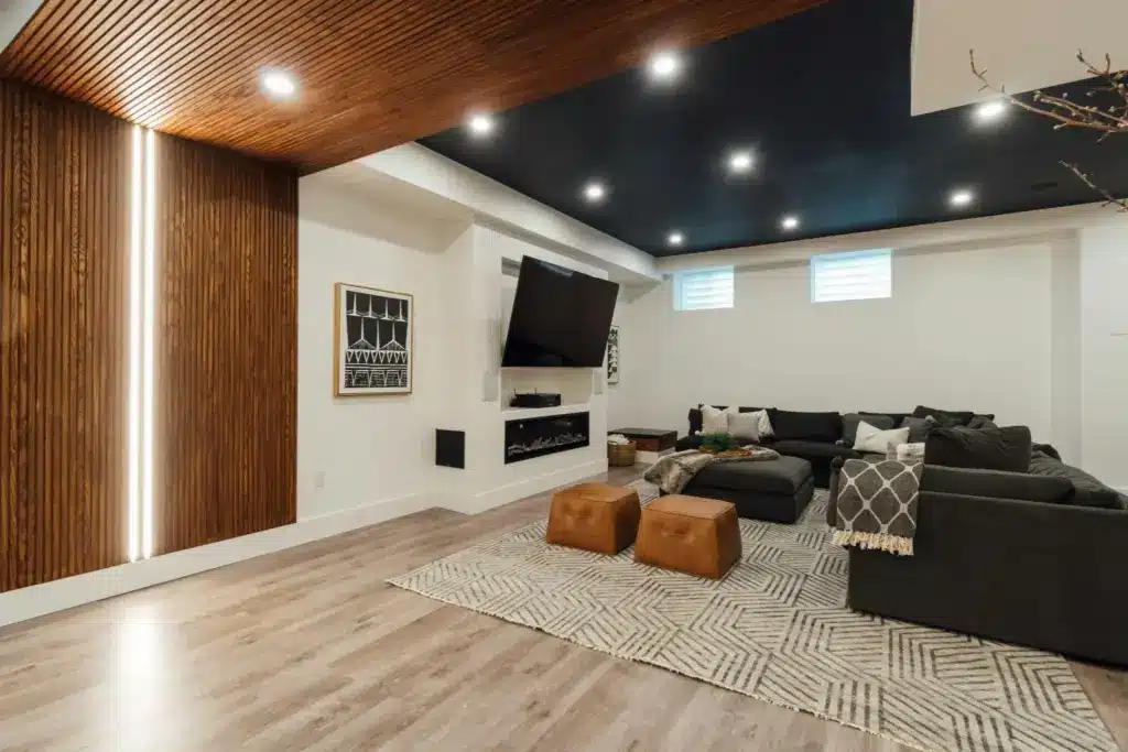 Modern living room with dark sectional sofa, geometric rug, and wood accented ceiling and walls