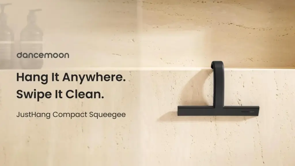Black squeegee with hook mounted on beige stone wall in modern bathroom setting