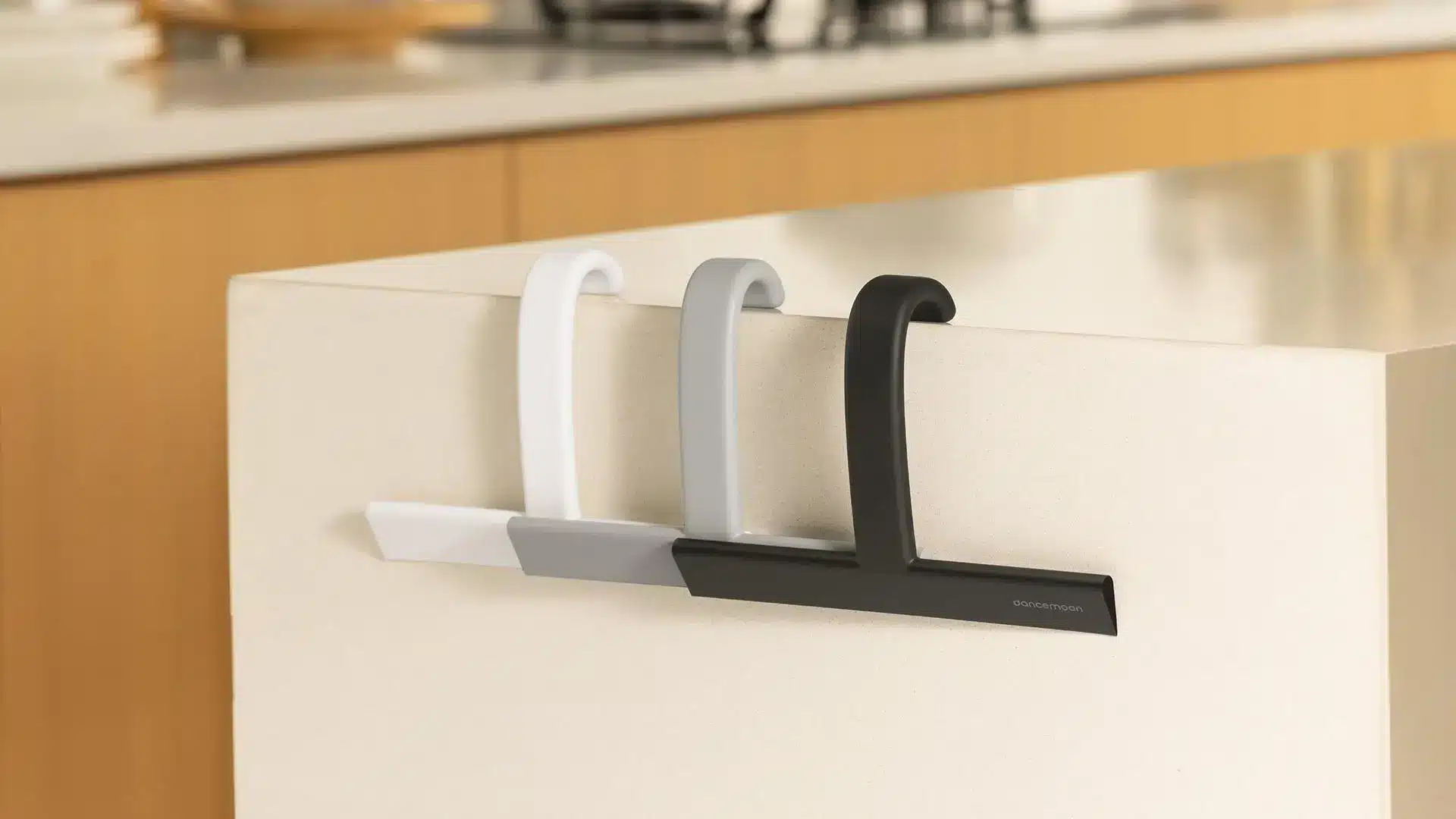 Three hangers in white, gray, and black on white cabinet in modern kitchen