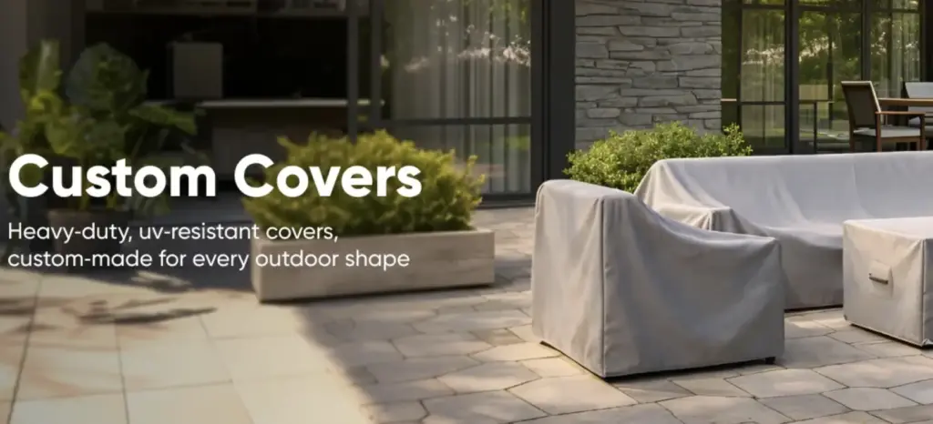 Patio Table Cover Ideas That Look Great and Last Outdoor patio furniture covered with gray protective fabric surrounded by greenery and stone tiles